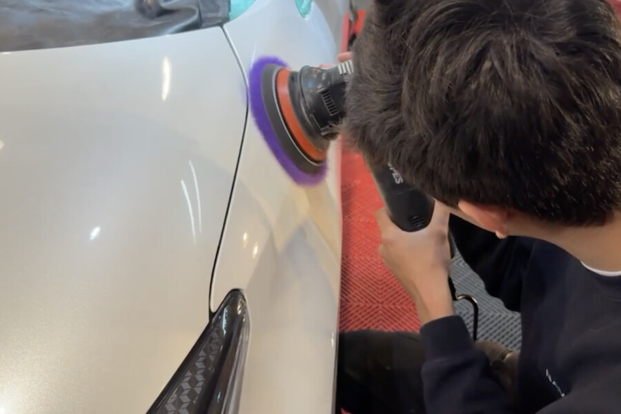 ポリッシャーで白い車のボディを磨くクレヴァーズ名古屋のスタッフ